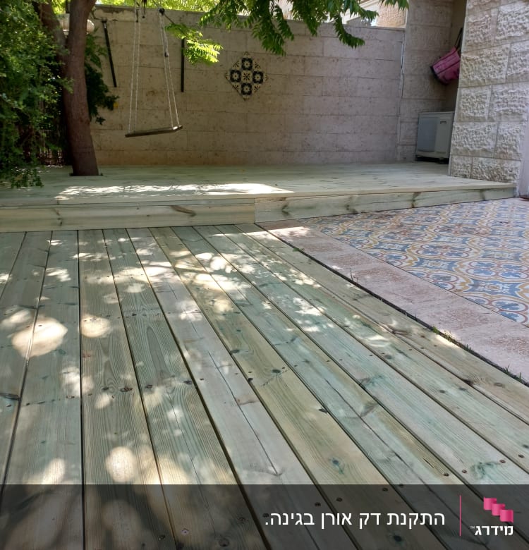 דק עץ בגינה עם נדנדה תלויה מעץ